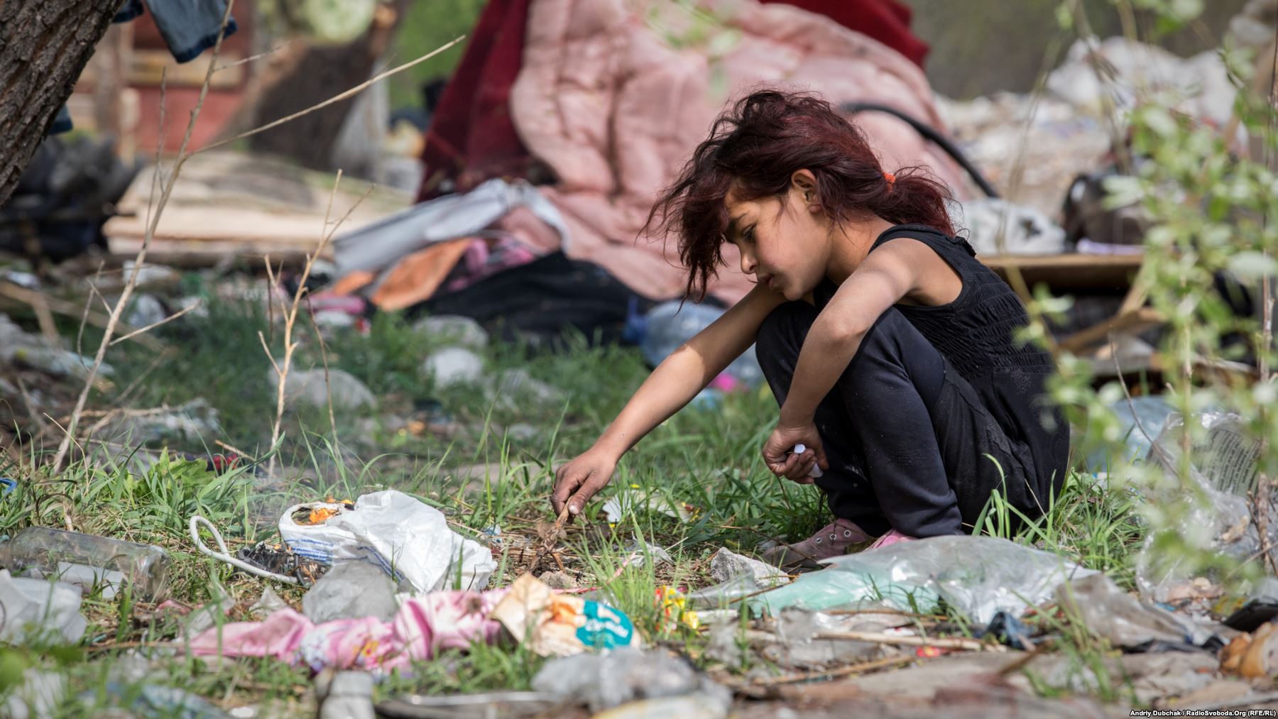Дівчинка зі стихійного поселення ромів палить багаття з целофанових пакетів