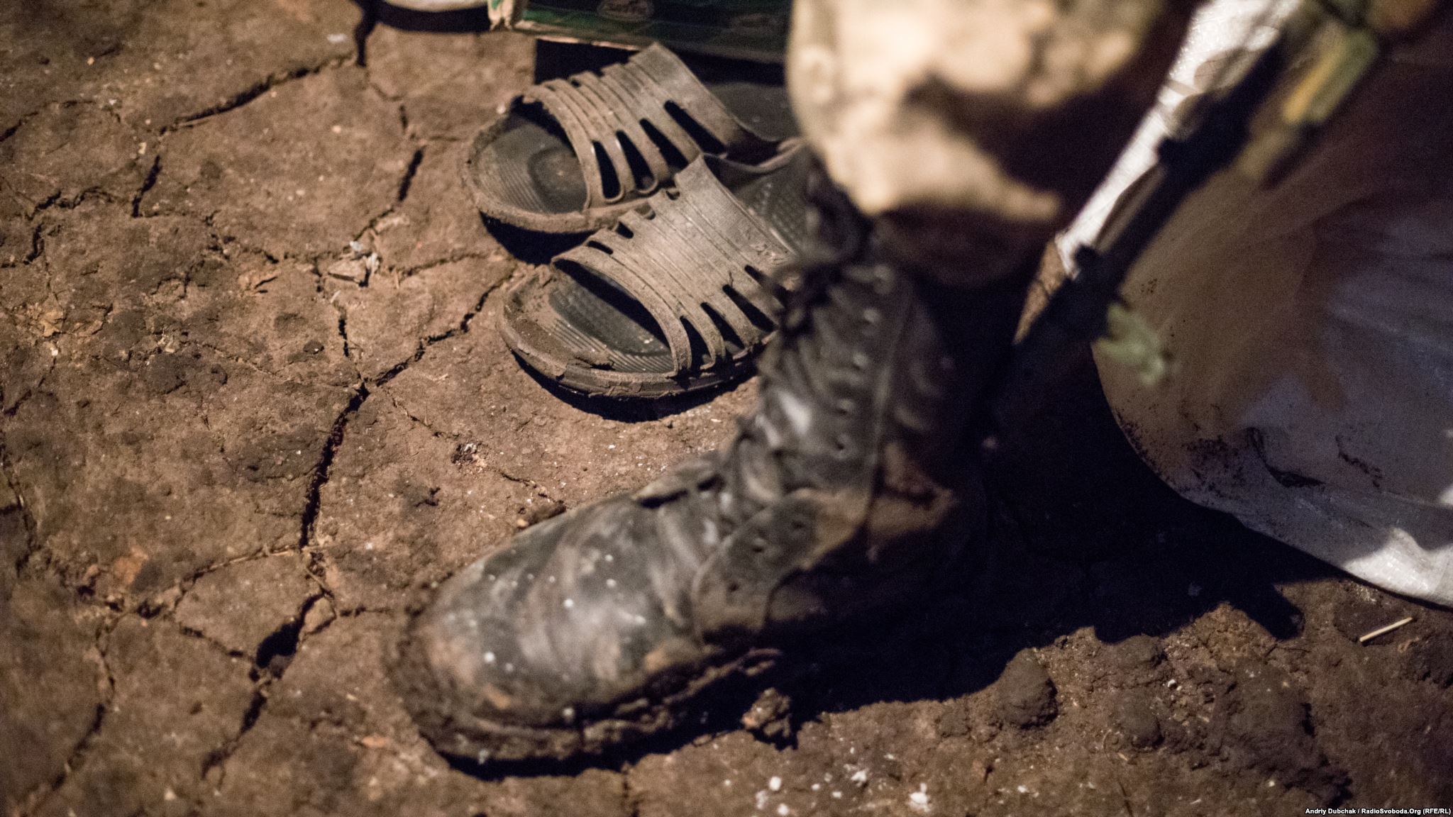 An earthen floor and home slippers can be seen in one of the inhabited dugouts on frontline (photo by ukrainian military photographer Andriy Dubchak)