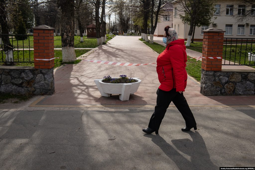 Жінка у медичній масці проходить повз закритого обмежувальною стрічкою входу до Калинівської лікарні. Фото - Андрій Дубчак